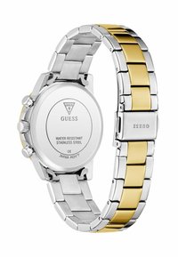 Montre en acier inoxydable bicolore argent et or avec un boîtier rond, des cadrans chronographes et un bracelet à maillons à motifs. Résistante à l'eau.