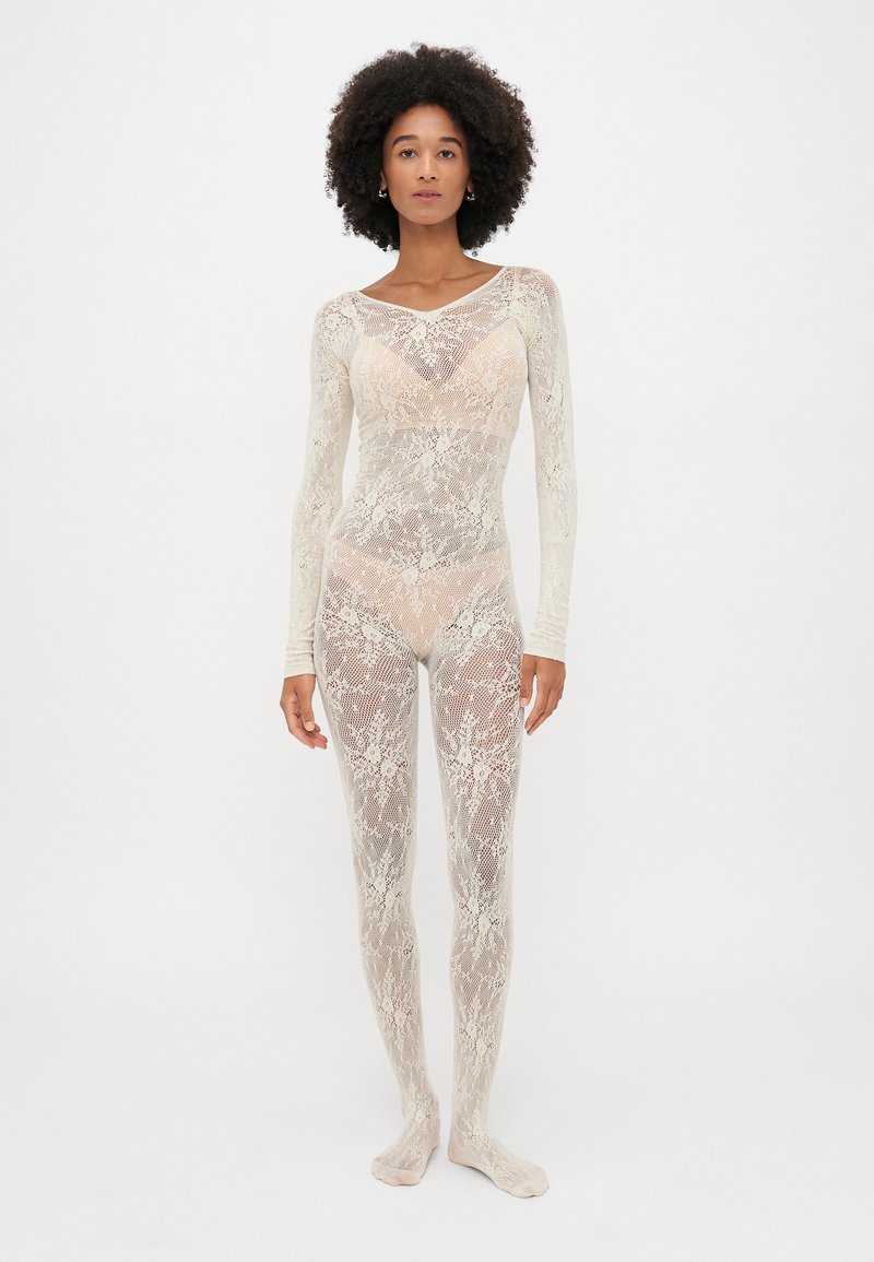 Δαντελένιο κορμάκι σε εκρού, με μακριά μανίκια, λουλουδάτα σχέδια και σφιχτή γραμμή. Ημι-διάφανο με απαλό υφασμά.