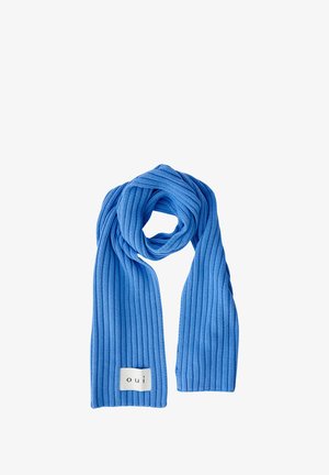 Écharpe tricotée bleue à côtes avec une texture douce, arborant une étiquette blanche avec "oui" à une extrémité. Longue et enroulée en forme de spirale.
