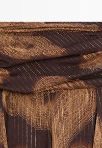 Tessuto marrone a motivo con accenti metallici dorati e linee verticali, con un design drappeggiato che crea texture e profondità.
