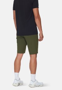 Mørk t-shirt, olivengrønne shorts og hvide sokker. Letvægtigt stof, afslappet snit og knælange shorts uden synlige mønstre eller detaljer.