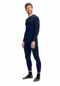 Marineblauwe thermoshirt met lange mouwen en bijpassende leggings van rekbare stof. Strak design met een gladde textuur en minimale branding op de borst.