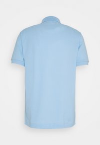 Polo bleu clair à manches courtes, col structuré et texture en coton lisse. Pas de logos ou motifs visibles.