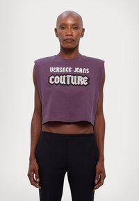 Lilla avkortet ermeløs topp laget av bomull med en dristig "Versace Jeans Couture" grafikk i hvit og svart skrift.