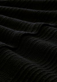 Schwarzer strukturierter Stoff mit einem welligen Muster, das ein weiches, gewebtes Erscheinungsbild und unterschiedliche Tiefen in seinen Rillen zeigt.