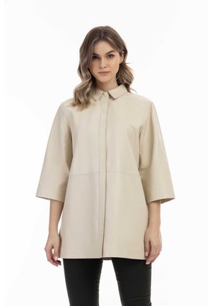 Giacca camicia in pelle color crema con colletto e maniche a tre quarti, dotata di chiusura centrale con bottoni e una texture liscia e raffinata.