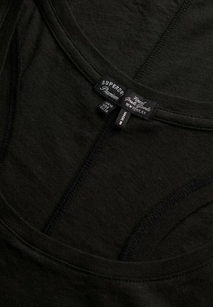 Sort bomuld tank top med rund halsudskæring, tynde stropper og syninger. Etiketter viser brand og plejeinformation. Glat tekstur.