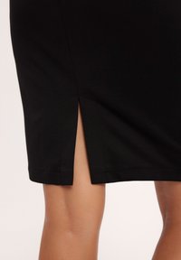 Czarna spódnica ołówkowa z bocznym rozcięciem. Tkanina jest gładka o matowym wykończeniu, z starannym szyciem i dopasowanym krojem.