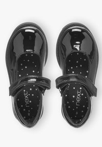 Zwarte gepatenteerde leren schoenen met een ronde neus, verstelbare band en zwart voering met sterpatroon. Gladde textuur en glanzende afwerking.