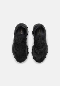 Black slip-on shoes with a textured upper featuring small round protrusions. Designed with a logo patch and cushioned soles for comfort.
