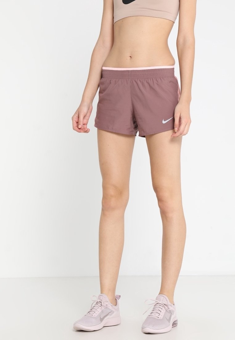 Helle mauvefarbene Sportshorts mit breitem elastischem Bund und kleinem Nike-Logo. Kombiniert mit einem beigen Crop-Top und hellen Sneakers.