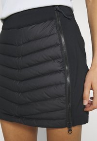 Czarna spódnica z wyściełanym wzorem, diagonalnymi przeszyciami, zamkiem błyskawicznym z boku oraz gładkim pasem w kontrastowym materiale.