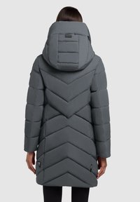 Grå polstret frakke med chevronmønster, stor hætte og en glat tekstur. Har sidelommer og et logo-tag på kanten.