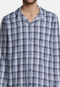 Camicia a maniche lunghe a quadri navy e azzurro chiaro con colletto a scollatura, tasca frontale e chiusura a bottoni. Realizzata in tessuto leggero.
