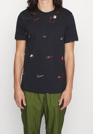 Zwart katoenen t-shirt met verspreide Nike-logo's in rood en wit. Klassieke pasvorm met korte mouwen, ronde hals en een zachte textuur.