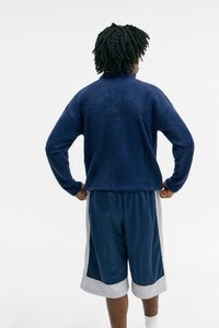 Navy blue textured sweater, loosely fitted, paired with knee-length navy shorts featuring a subtle striped pattern and white side accents.