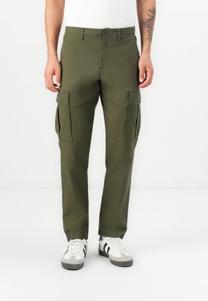 Olive green cargo pants made of cotton, featuring side pockets, a straight cut, and subtle stitching details. Paired with white sneakers.