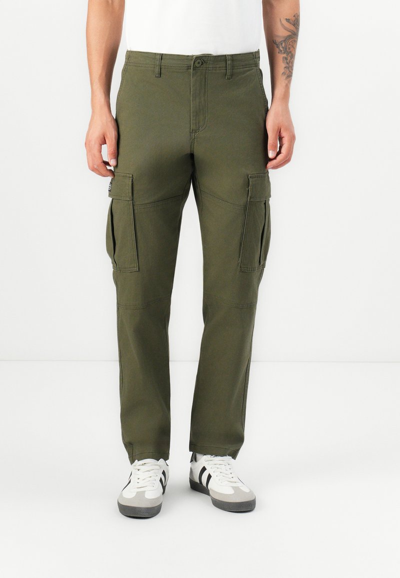 Olive green cargo pants made of cotton, featuring side pockets, a straight cut, and subtle stitching details. Paired with white sneakers.