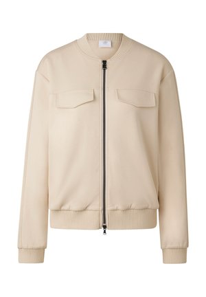Béžová bomber bunda se zapínáním na přední zip, dvěma kapsami na hrudi, žebrovanými manžetami a spodním lemem. Vyrobená z hladké, lehké látky.