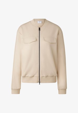 Beige Bomberjacke mit einem Frontreißverschluss, zwei Brusttaschen, gerippten Bündchen und Saum. Hergestellt aus einem glatten, leichten Stoff.