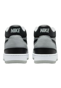 Mid-top sneakers featuring black leather, light grey accents, and white soles. Rear view shows prominent "NIKE" logo in white on the heel.