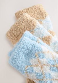 Three textured, fluffy socks in light blue, cream, and tan, with a diamond pattern on the blue sock. Soft and plush material.