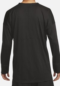 Zwarte longsleeve top met een geribbelde textuur. Bevat een ronde hals en een relaxte pasvorm, met zichtbare stiksels en zijsplitten aan de zoom.
