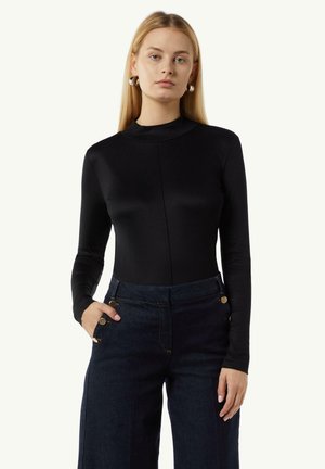 Black long-sleeve bodysuit with a high neckline, made of smooth fabric. Paired with dark denim wide-leg pants featuring gold-tone hardware.