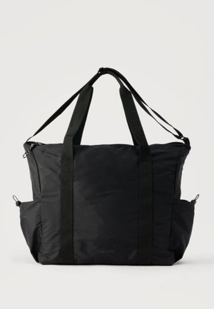 Sac fourre-tout en nylon noir avec longues poignées, bandoulière ajustable, poches latérales et fermeture éclair sur un fond uni.