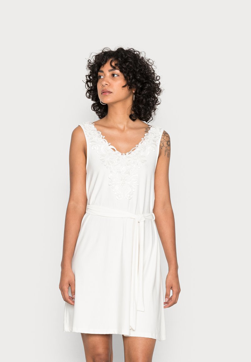 Vestido branco sem mangas com bordado de renda na gola e um cinto amarrado na cintura para um ajuste ajustável. Tecido suave com um corte descontraído.