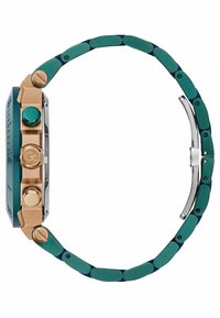 Sānskats uz zelta un tērkzila metāla pulksteni ar teksturētu rāmīti, trim pogām un savienotu siksniņu ar aizdari, uz balta fona.