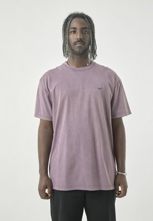 Kurzärmliges, übergroßes lila T-Shirt mit einem verwaschenen Look. Mit kleinem, dunklem Logo auf der Brust und rundem Halsausschnitt.