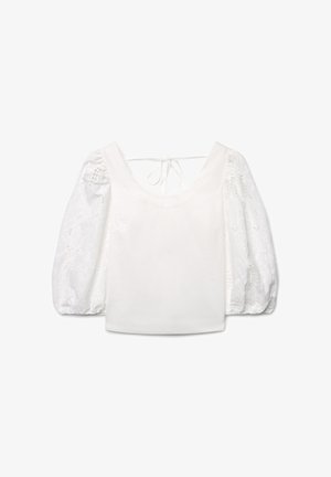 Blouse blanche avec manches en dentelle bouffantes, encolure dégagée et fermeture par nœud dans le dos, réalisée en tissu lisse et à motifs.