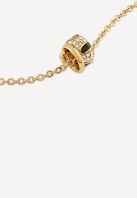 Bracciale color oro con design a catena collegata. Presenta un ciondolo rotondo decorato con cristalli trasparenti e accenti neri. Meccanismo di chiusura semplice.