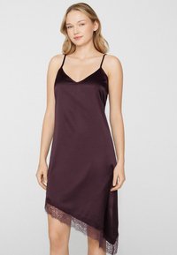 Camisón de satén en color púrpura intenso con tirantes delgados, escote en V y dobladillo asimétrico, con delicados detalles de encaje en la parte inferior.