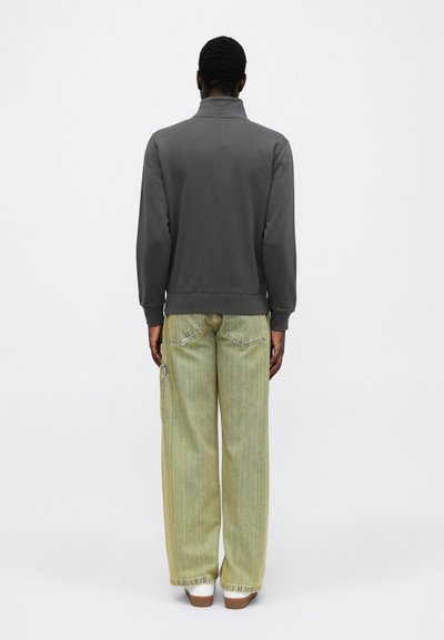 Gray sweatshirt with a stand-up collar and ribbed hem, paired with light green baggy jeans featuring visible stitching and side pockets.