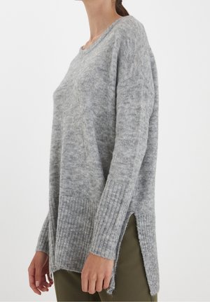 Pull en tricot gris avec une texture côtelée, des fentes latérales et une coupe décontractée. Présente des manches longues et un col rond classique.