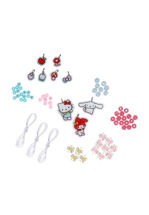 Breloques personnages et fruits, perles colorées, perles en forme de fleur et cordons élastiques blancs disposés sur un fond blanc pour la fabrication de bijoux.