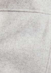 Jasnoszary materiał o miękkiej, teksturowanej powierzchni, z delikatnymi odcieniami koloru i gładkim wykończeniem. Brak widocznych wzorów lub akcentów.