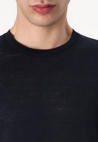 Svart crew-neck t-skjorte laget av lett stoff med en myk tekstur og svak glans. Minimalistisk design uten synlige logoer eller mønstre.