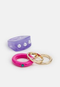 Quatro anéis: um anel de resina lavanda com três pérolas falsas, um anel glossy rosa com uma gema verde, e duas alianças em metal dourado.