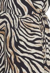 Kietova mekko, jossa on vaaleanbeige ja musta seeprahainkuvio. Ominaisuuksiin kuuluu pehmeä kangas, vyötärön sitomisviimeistely ja sujuva siluetti.