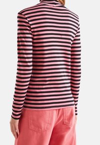 Långärmad polokrage i rosa och svarta horisontella ränder, med en mjuk textur och figurnära design, matchad med rosa byxor.