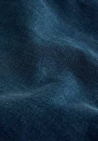 Donkerblauwe denimstof met een gladde textuur en subtiele kleurvariaties, met een licht gekreukeld uiterlijk.