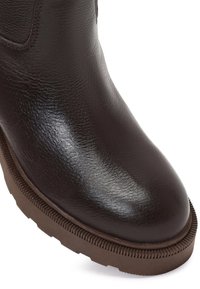 Bruine leren enkellaars met een gladde, glanzende afwerking, ronde neus en een getextureerde bruine rubberen zool. Versterkte stiksels zichtbaar.