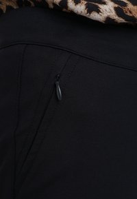 Black pants with a smooth texture, featuring a slim design and a small zippered pocket on the side. Accents include contrasting stitching.