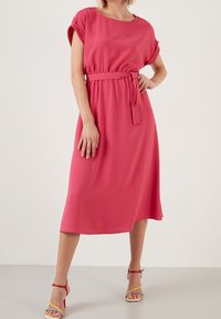 Rosa, knälång klänning med korta ärmar och midjebälte. Tillverkad av ett lätt material med en slät yta och en avslappnad passform.