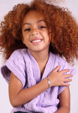 Pull en maille lilas avec des manches courtes, mettant en valeur un bracelet en argent avec un pendentif floral au poignet d'un enfant souriant.