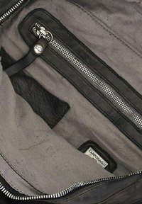 Interior de bolso de cuero negro con textura suave, forrado con tela gris, bolsillo con cremallera y una etiqueta que dice "Campomaggi".