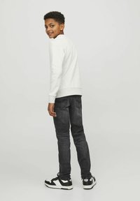 Sudadera gris claro, jeans negros ajustados y zapatillas negras. Diseño sencillo con puños y dobladillo acanalados, ajuste casual y estilo simple.